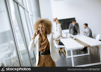 Young African American businesswoman standing and using mobile phone in the modern office
