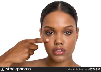 Young African American female model with healthy smooth skin and natural makeup touching cheek and looking at camera while representing cosmetology industry against white background. Ethnic woman with soft skin touching face