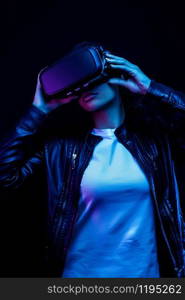 Young african american girl playing game using VR glasses, enjoying 360 degree virtual reality headset for gaming, isolated on black background in neon light