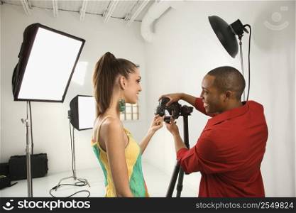Young African American male adult and Caucasian young female adult previewing image on digital camera.