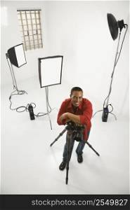 Young African American male adult photographer posing in studio.