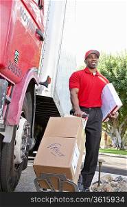 Young African American male standing with packages near delivery truck