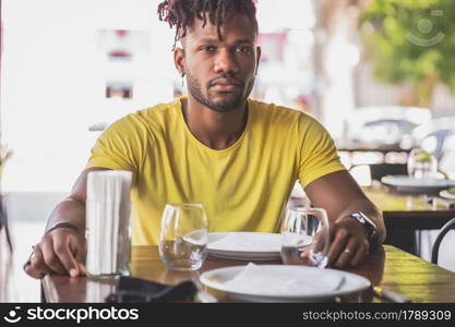 Young african american man looking at the camera while sitting at a restaurant.