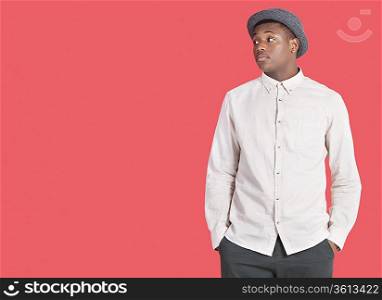 Young African American man looking sideways over red background