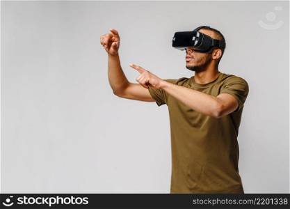 Young African American man wearing vr virtual reality headset over grey background.. Young African American man wearing vr virtual reality headset over grey background