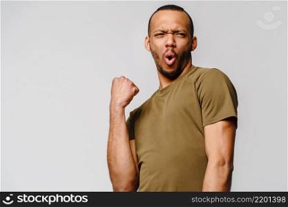 Young African-American man yes win gesturing over light grey background.. Young African-American man yes win gesturing over light grey background