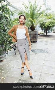 Young African American mixed race woman in brown jacket, midi pencil skirt with front slit, high heel shoe with belt strap in park or street outdoor. White t shirt mock up. Full body fall portrait. Young African American woman in park, white shirt mock up. Fall season