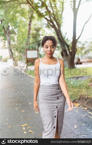 Young African American mixed race woman in midi pencil skirt with front button slit in park or street outdoor. White t shirt mock up. Fall season. Young African American woman in park, white shirt mock up. Fall season
