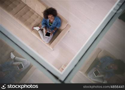 Young african american woman at home relaxing in her luxury lliving room reading a digital tablet PC surf internet and work top view