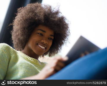 Young african american woman at home relaxing in her luxury lliving room reading a digital tablet surf internet and work