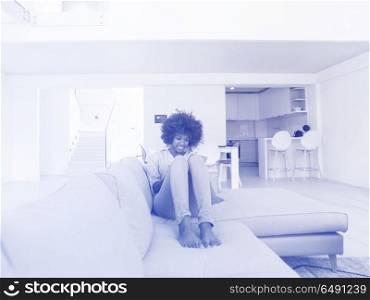 Young african american woman at home relaxing in her luxury lliving room reading a digital tablet surf internet and work. african american woman at home using digital tablet