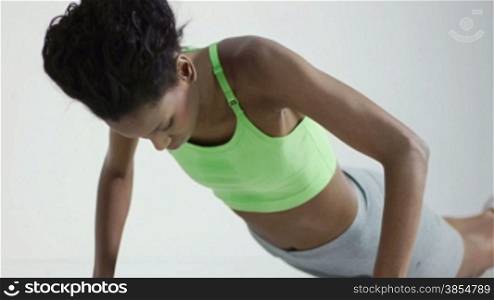 Young african american woman in sportswear doing push ups in gym