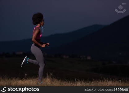 young African american woman runner with headphones jogging outdoors in nature beautiful summer night - Fitness, people and healthy lifestyle