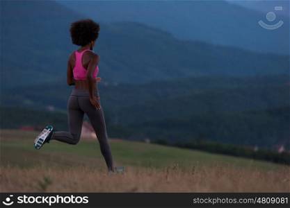 young African american woman runner with headphones jogging outdoors in nature beautiful summer night - Fitness, people and healthy lifestyle