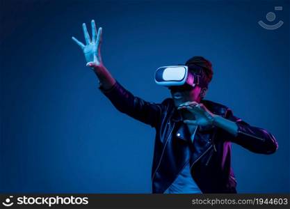 Young african-american woman using VR-glasses in neon light