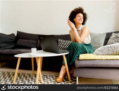 Young african american woman web-surfing internet and sitting on sofa