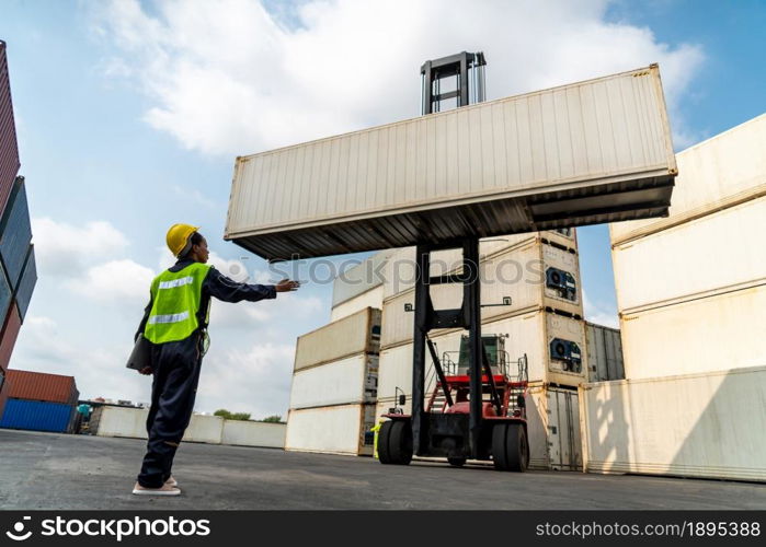 Young African American woman worker at overseas shipping container yard . Logistics supply chain management and international goods export concept .. Young African American woman worker at overseas shipping container yard