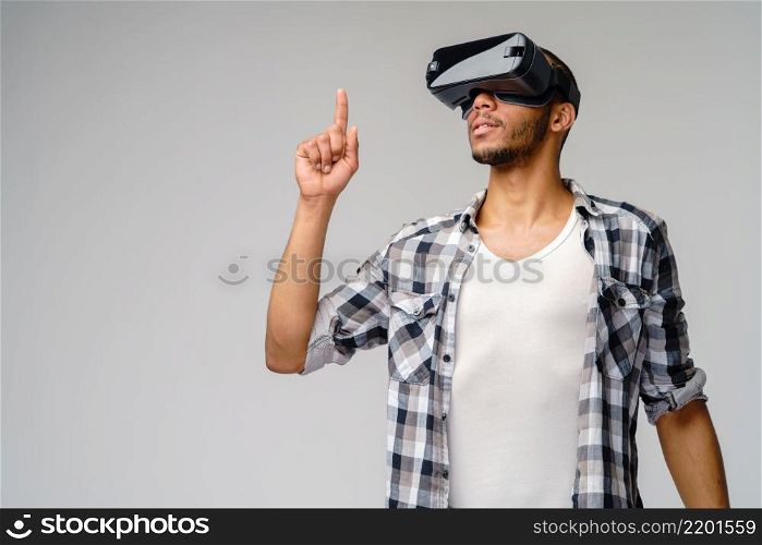 Young African-American young man wearing vr virtual reality headset over light grey background.. Young African-American young man wearing vr virtual reality headset over light grey background