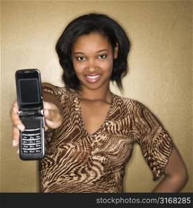 Young African-American young woman holding cellphone out to viewer.