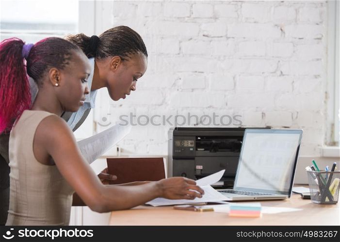 Young african business women in office working together on laptop