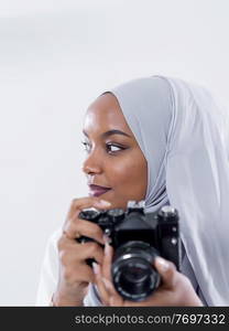 young  african modern muslim woman using retro camera wearing hijab clothes isolated on white background