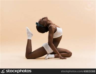 Young African woman doing yoga in stretching position