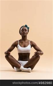 Young African woman in the lotus meditation position doing yoga