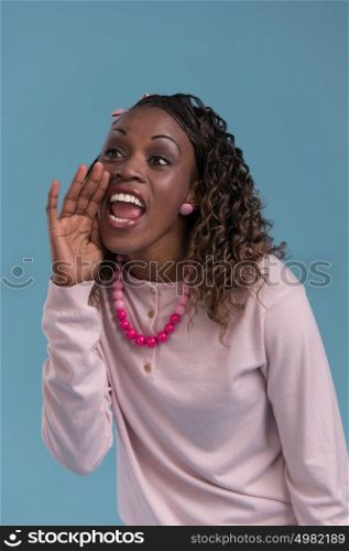 Young african woman shout and scream using her hands as tube, studio shoot isolated on blue