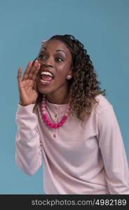 Young african woman shout and scream using her hands as tube, studio shoot isolated on blue