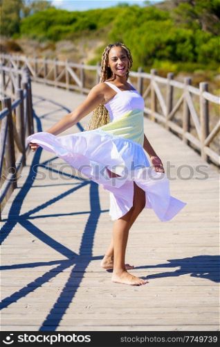 Young African woman wearing a beautiful dress on a boardwalk on the beach.. African woman wearing a beautiful dress on a boardwalk on the beach.
