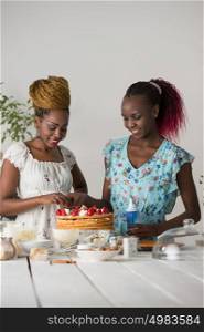 Young african women at the kitchen cooking cake with strawberry