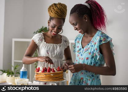 Young african women at the kitchen cooking cake with strawberry