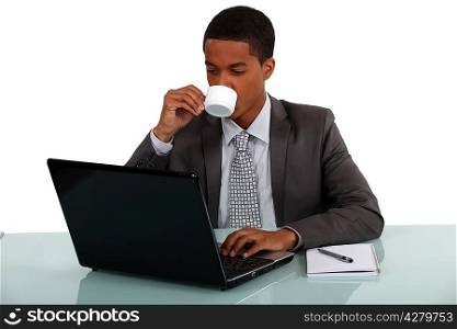 young Afro-American businessman working on his laptop and drinking his coffee