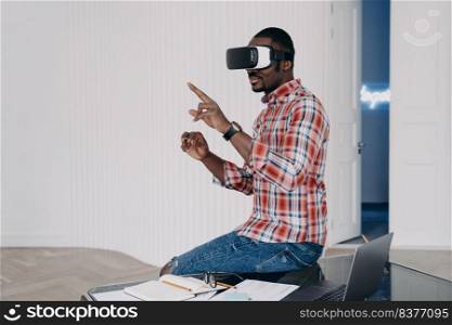 Young afro businessman has virtual lesson. African american man in vr glasses in living room. Virtual reality goggles using. Modern education and electronic wireless technology for business.. Young afro businessman has virtual lesson. Virtual reality goggles using for business.