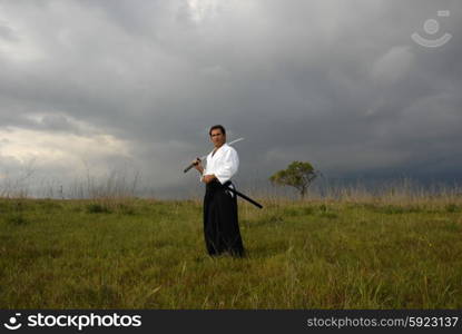 young aikido man with a sword outdoors