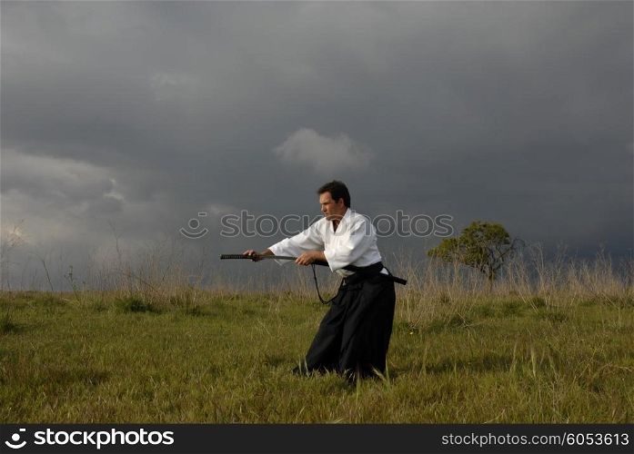 young aikido man with a sword outdoors