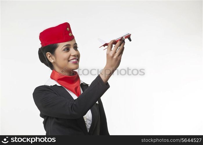 Young airhostess holding toy airplane isolated over white background