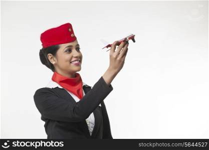 Young airhostess holding toy airplane isolated over white background