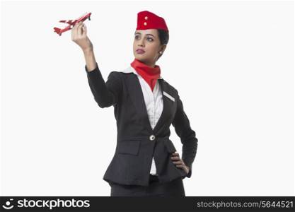 Young airhostess looking at toy airplane isolated over white background
