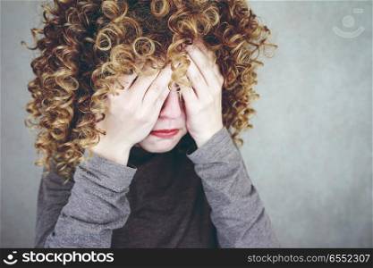Young and afraid woman covering her face with her hands