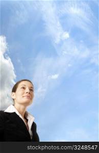 Young and ambitious businesswoman looks at the future in front of the blue sky.
