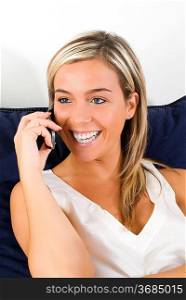 young and attactive blond woman talking with a mobile and one evening in her bedroom before to sleep