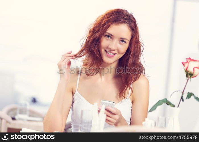 Young and attractive woman sitting in cafe and using cellphone. Texting massages at cafe