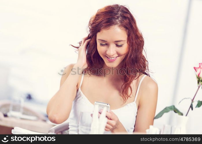 Young and attractive woman sitting in cafe and using cellphone. Texting massages at cafe