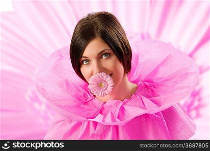 young and beautiful girl with pink collar paper keeping a pink flower in her mouth