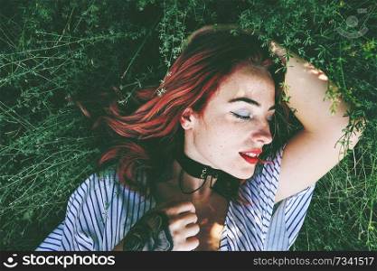 Young and beautiful redhead woman posing surrounded by nature                               