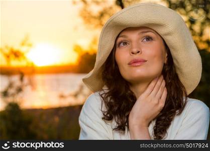 Young and beautiful woman wearing a hat in sunset light