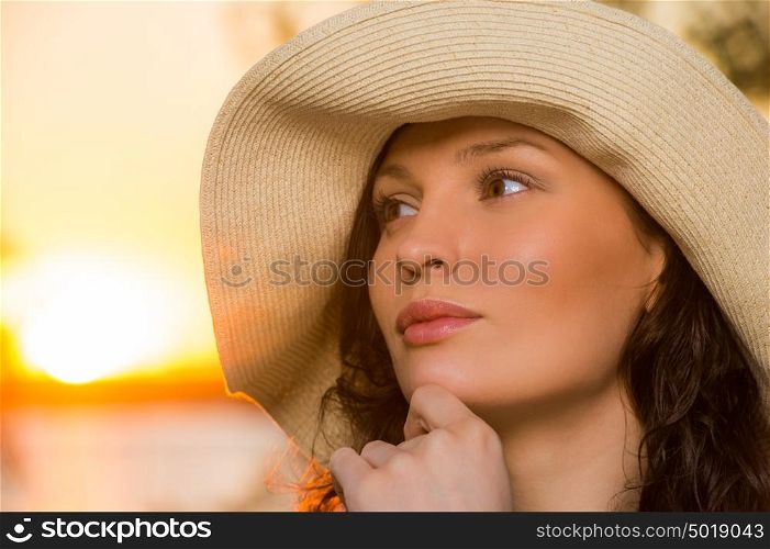 Young and beautiful woman wearing a hat in sunset light