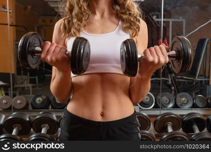 Young and beautiful woman working out with dumbbells in gym - Image