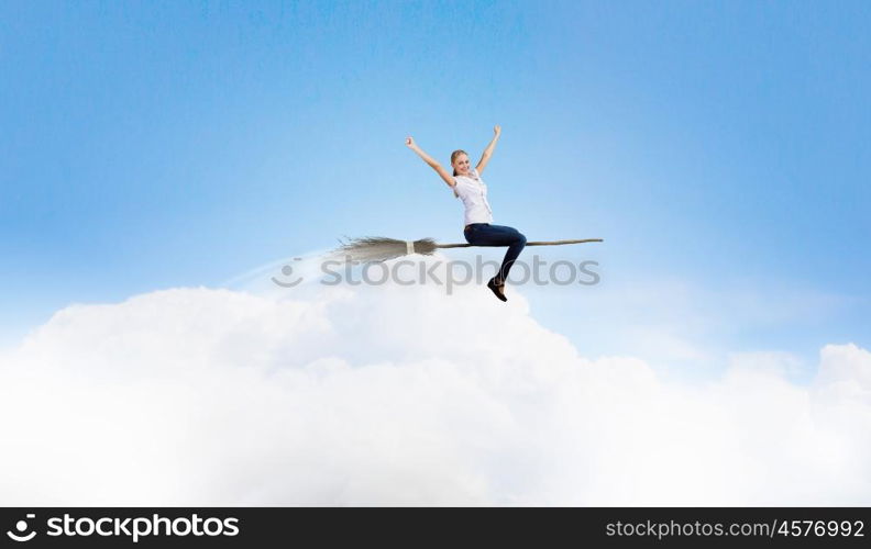 Young and careless. Happy young woman flying in sky on broom